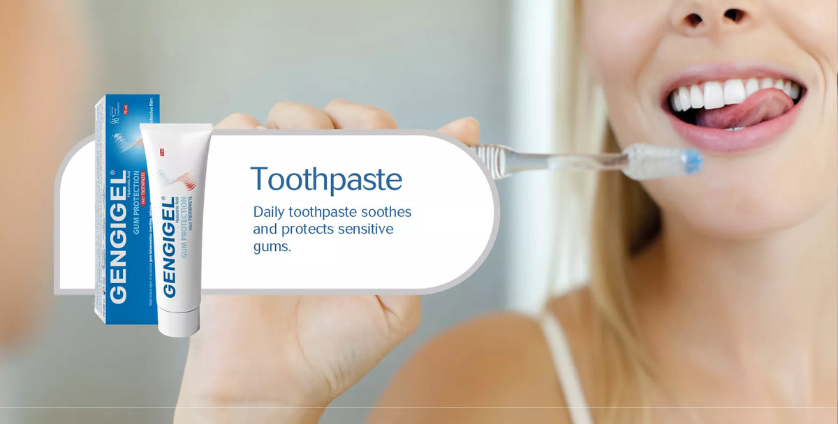 A close-up of a woman holding a tube of Gengigel toothpaste and its box, with a toothbrush in her mouth, against a softly blurred bathroom background.